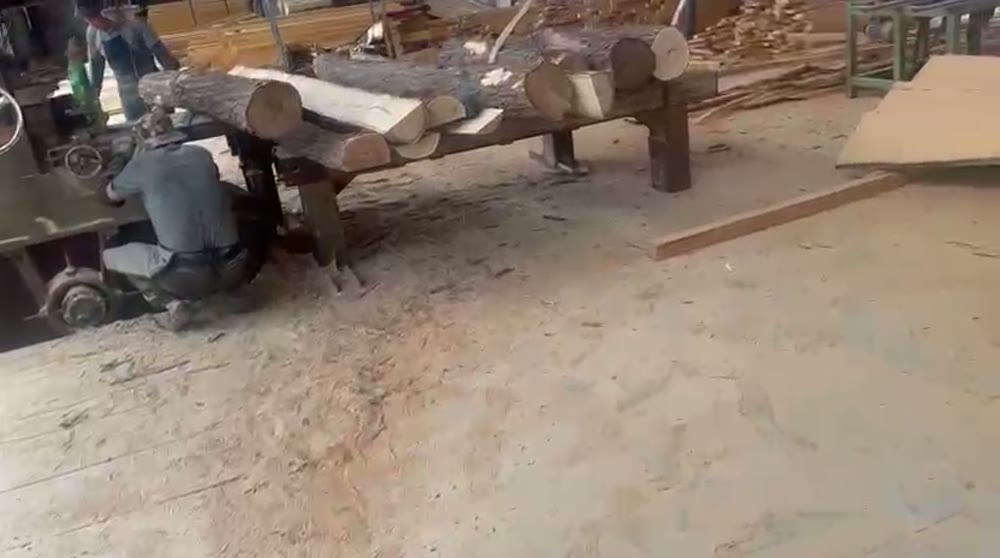 Workers milling raw Robinia hardwood logs into planks at the Hon Playground factory for the customized pirate ship playground.